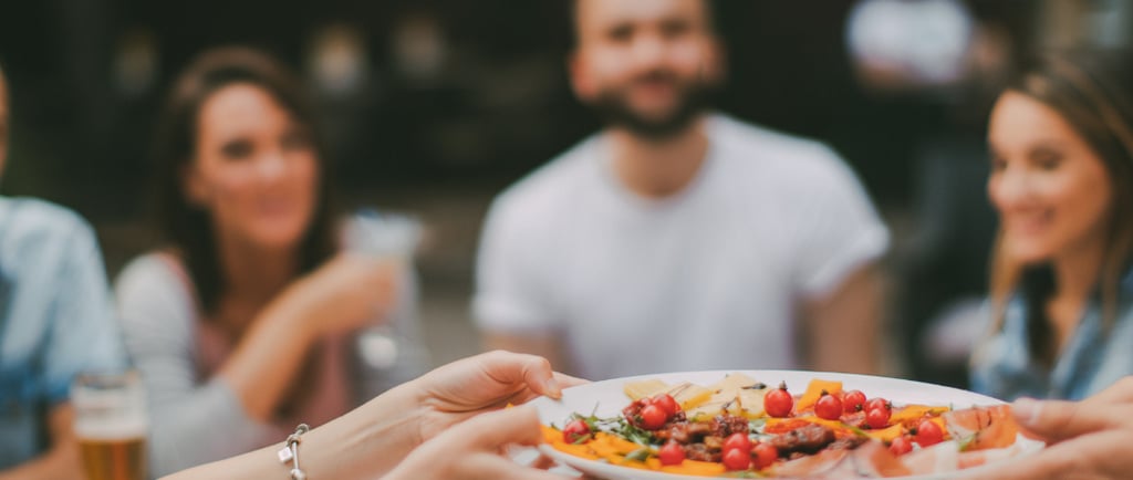 several relaxed happy people are passing beautiful food around a dinner table