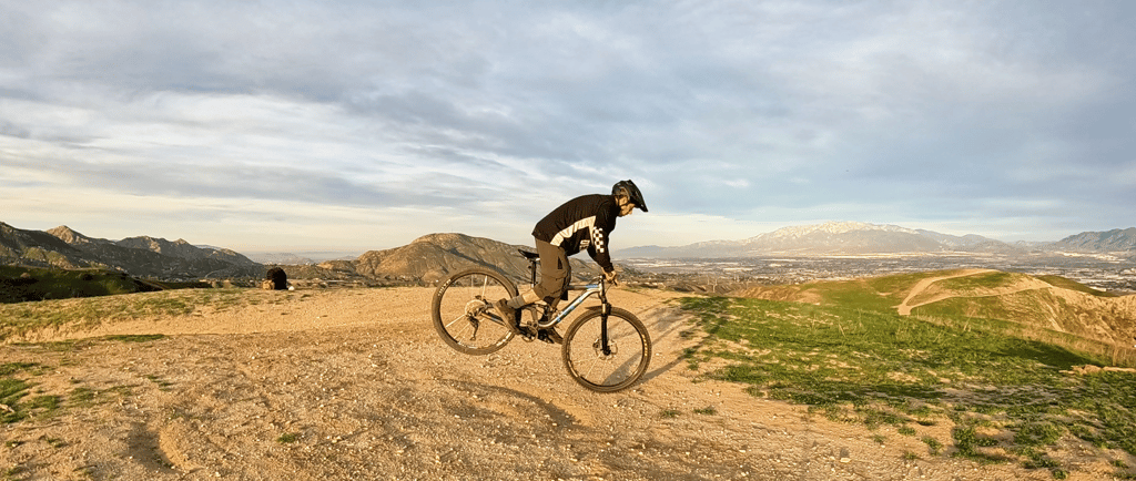 rider doing a rear wheel lift with flat pedals on a mountain bike