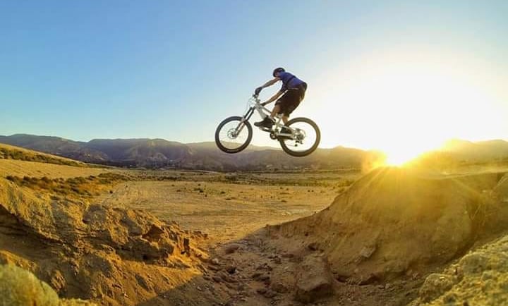 Mountain biker hitting a canyon gap jump at sunrise, showcasing advanced freeride technique