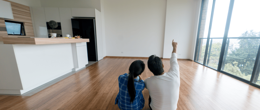 a man and woman sitting on a hard wood floor