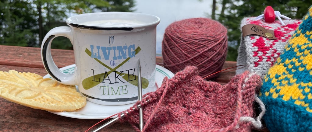 Latte and knitting project sitting next to a lake