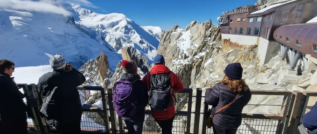 Tourists enjoying panoramic views of the French Alps from the Aiguille du Midi terrace on a Chamonix