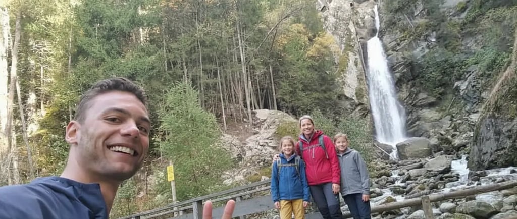 Happy family taking a selfie by a scenic alpine waterfall during a nature walk on a Chamonix guided 