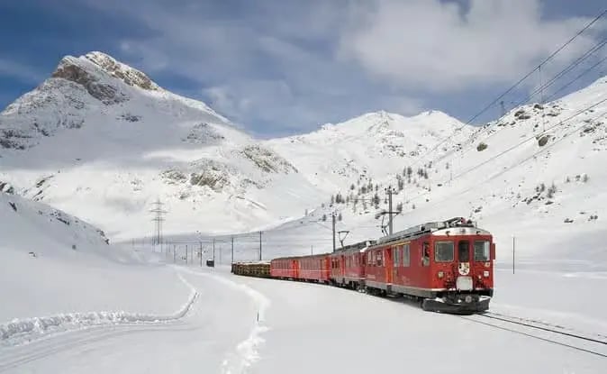 Red Bernina Express train traveling through high alpine peaks