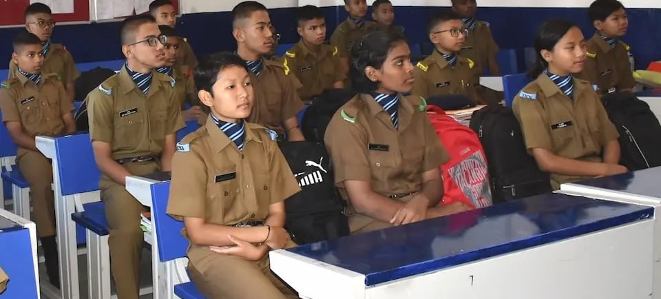 Girls in uniform sitting in a classroom at Sainik School, where doors open for females in Sainik Schools.  promoting female