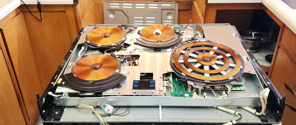 Top glass removed induction cooktop, all coils are visible and it's being repaired.
