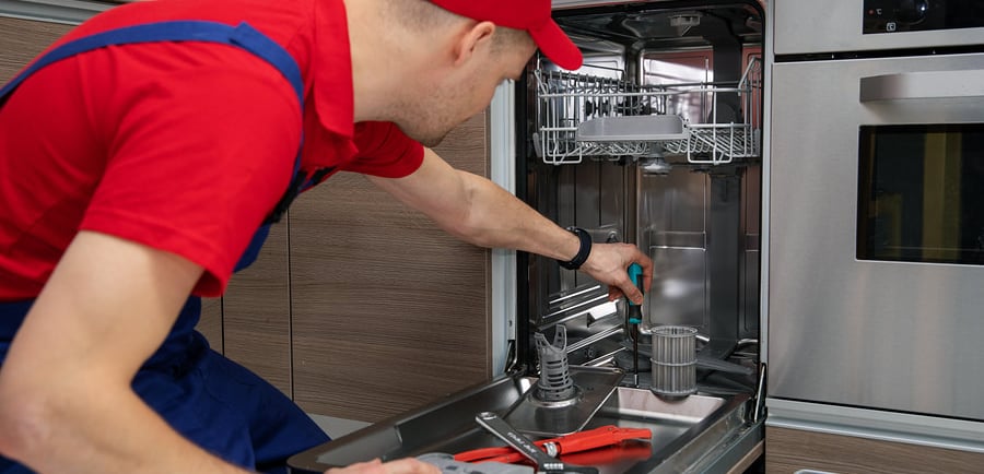 a person red hat repairing a dishwasher 