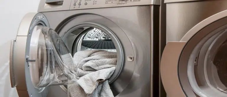 a dryer and front load washer and some towels inside the dryer