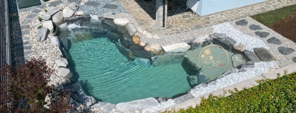 piscina con rocce e sabbia davanti al portico di casa