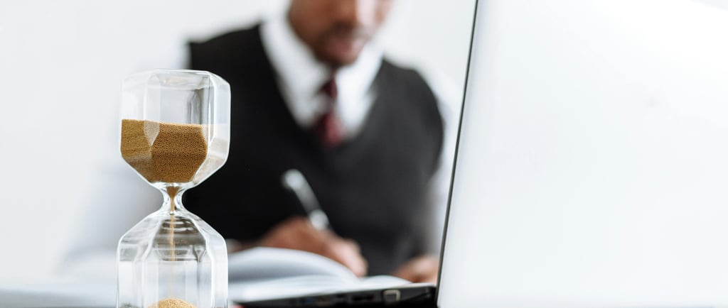 Optimiza tu tiempo con Cuvo: reloj de arena junto a persona trabajando en análisis de datos.