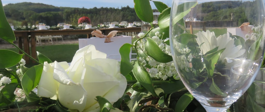 Elegant outdoor wedding table setting with white roses, greenery, and a wine glass. Dordogne