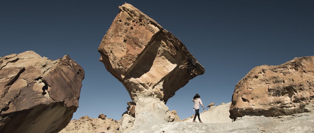 Rocky background with clear sky and a person walking towards unknown direction.