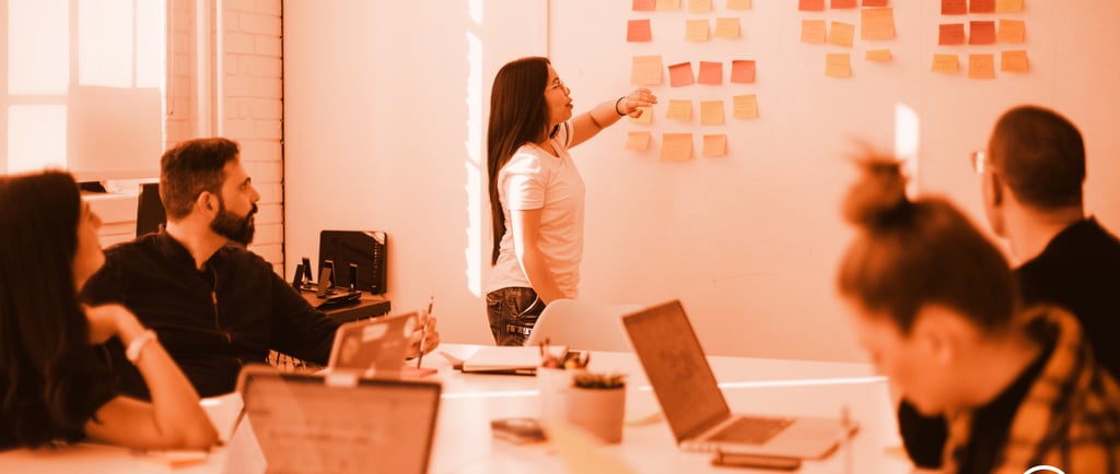 a woman standing in front of a white board with sticky notes on it