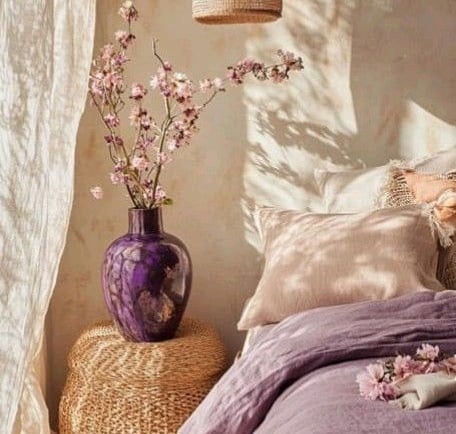 a bed with a purple bedding and a vase with flowers