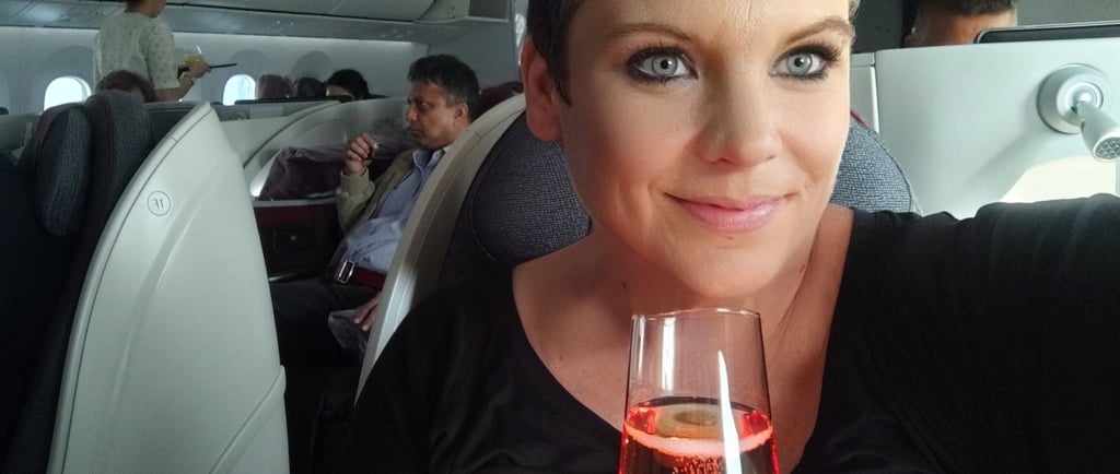 a woman holding a glass of wine in a plane