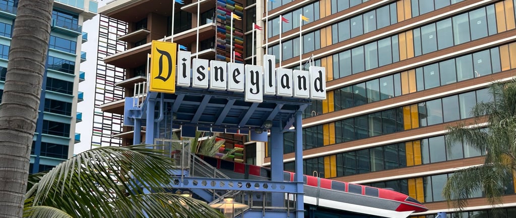 A retro-style "Disneyland" sign rests above the themed pool slide in the Disneyland Hotel courtyard,