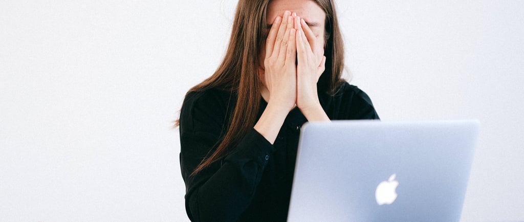 a woman sitting at a desk with her hands covering her face