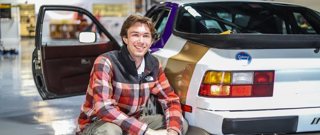 Luke Gilmore sitting next to a Porsche 944.