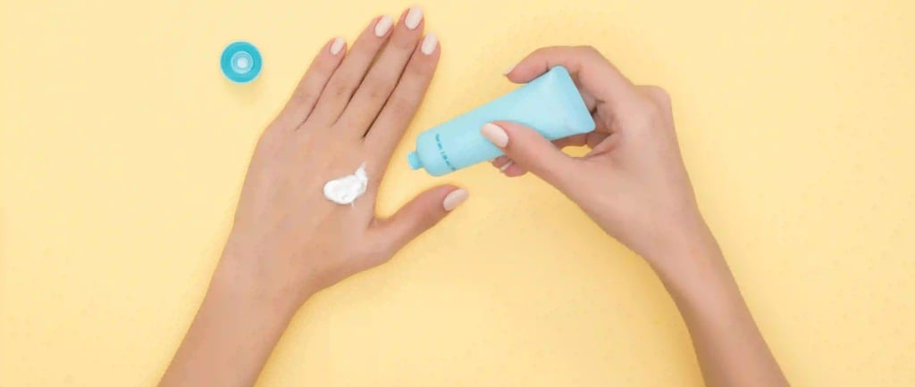 a woman's hands holding a tube of cream