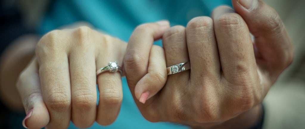 two hands of a couple with engagement rings