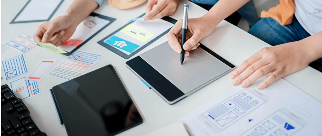 a person sitting at a table with a tablet and a pen