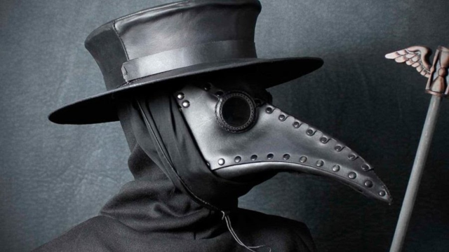Pessoa usando uma máscara de médico da peste, de couro preto, com bico alongado e óculos redondos,