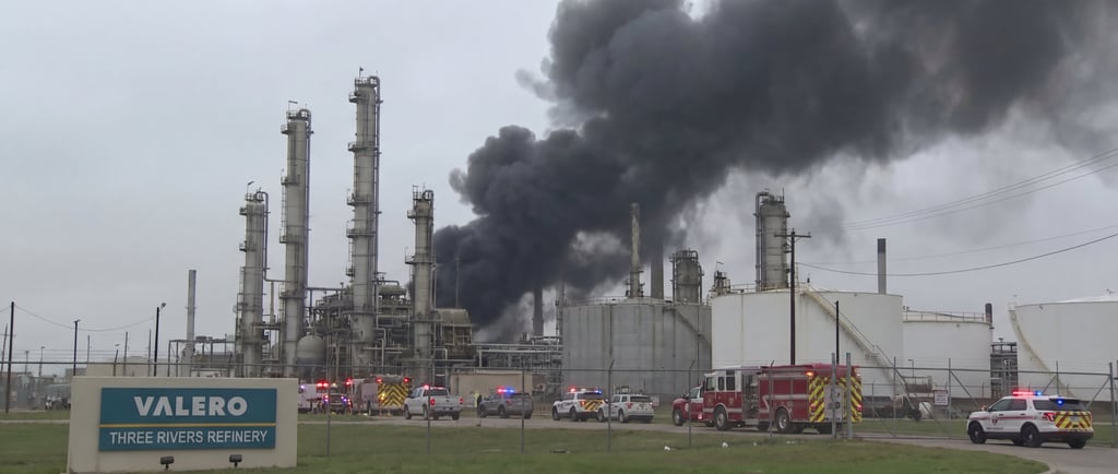 Black smoke billows from the Valero Three Rivers Refinery as fire trucks and emergency vehicles respond.