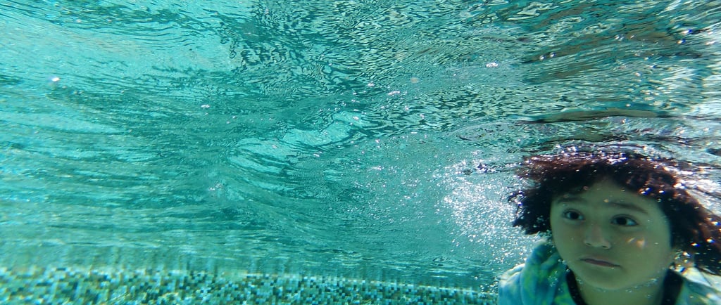 a young girl swimming in a pool with a blue shirt