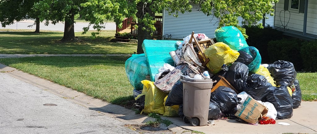 Large curbside pile of bagged trash, furniture, and bulky household items in Kansas City, Kansas.