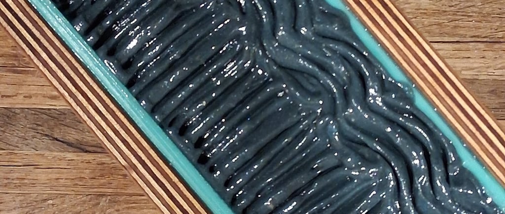 Overhead view of a handmade wooden soap mold filled with swirling charcoal grey artisan soap batter.