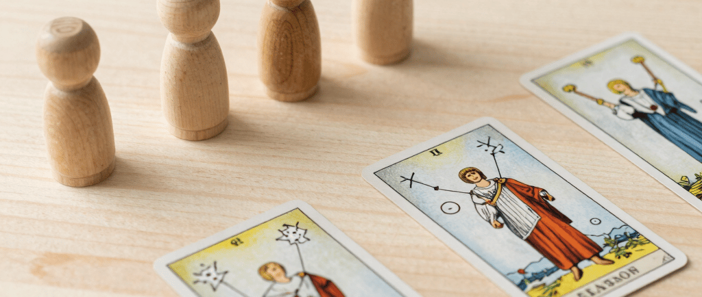 cartas de tarot con figuritas de madera en una mesa clara de madera