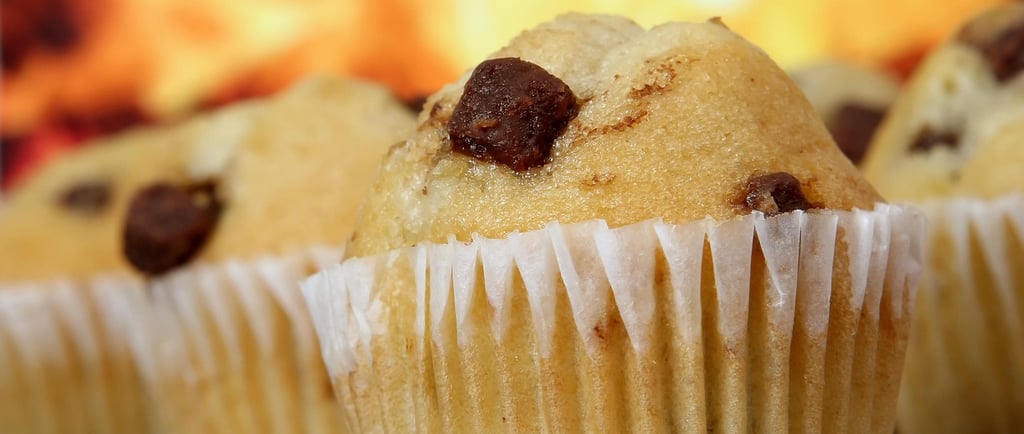 Close-up of freshly baked chocolate chip muffins on a cooling rack with a warm background.