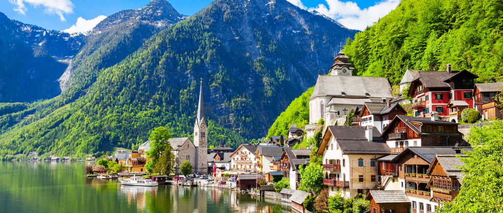 Panoramic view of Hallstatt, a charming lakeside village with historic buildings, lush mountains, and serene water in