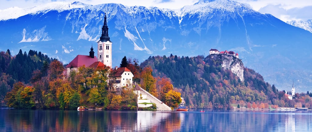 Scenic Lake Bled in Slovenia featuring the Pilgrimage Church on Bled Island with snow-capped Julian Alps.