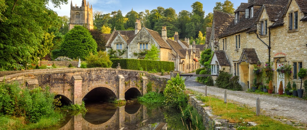 A stone arch bridge over a river in the picturesque English village of Castle Combe, Cotswolds.