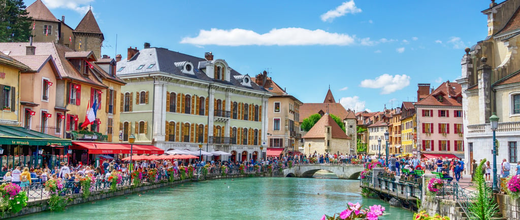 Picturesque Annecy, France canalside with colorful buildings, bustling restaurants, people, and historic architecture under