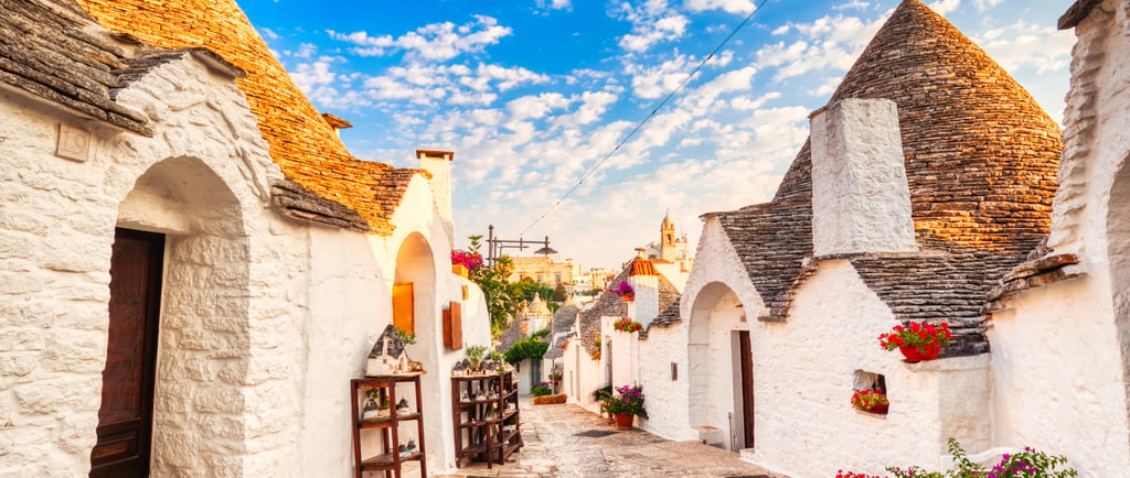 Traditional white trulli houses with conical stone roofs in a scenic street of Alberobello, Italy.