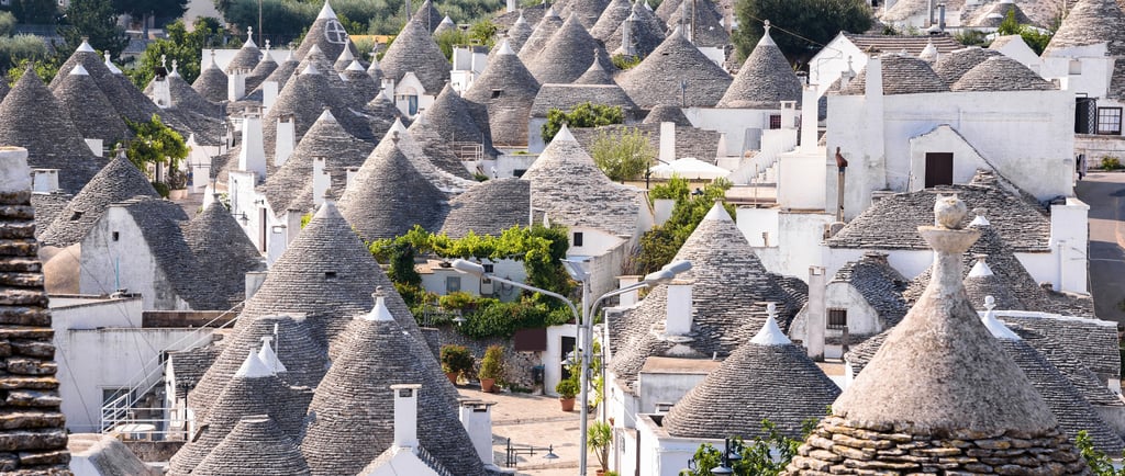 Panoramic view of traditional white trulli houses with conical stone roofs in Alberobello, Puglia, Italy.