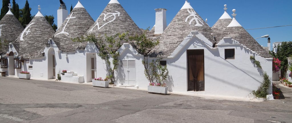 Traditional white trulli houses with conical stone roofs in Alberobello, Puglia, Italy.