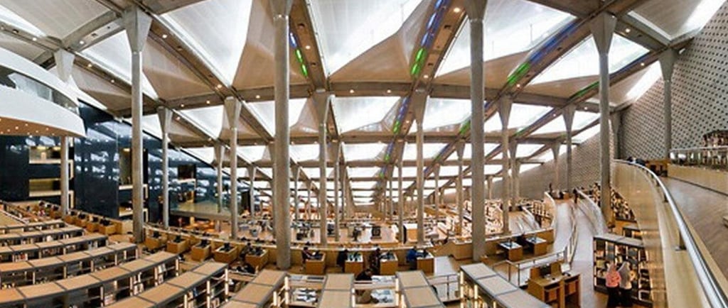 Modern interior of the Bibliotheca Alexandrina library in Egypt featuring tiered reading areas and skylights.