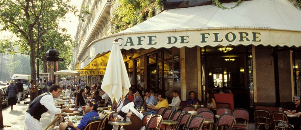 Waiters serve patrons at the outdoor seating of the iconic Cafe de Flore in Paris.