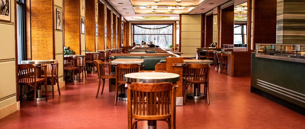 Elegant cafe interior with wooden chairs, red flooring, and modern lighting fixtures.