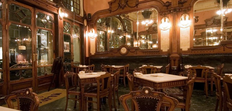 Elegant Art Nouveau interior of Majestic Cafe in Porto featuring ornate wood carvings and mirrors.