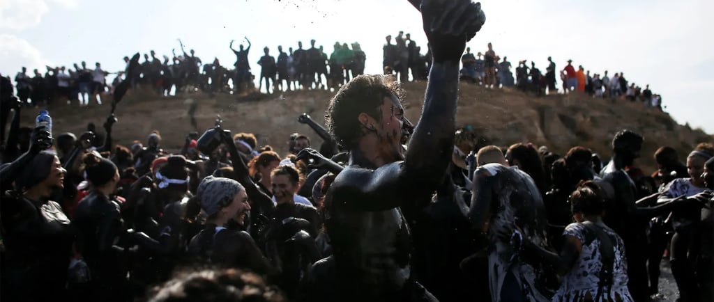 Crowd of festival participants covered in black mud at the Boryeong Mud Festival in South Korea.