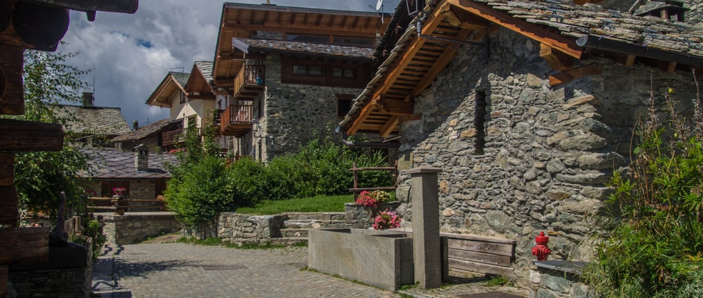 Rustic stone houses and a cobblestone street in a traditional European mountain village.
