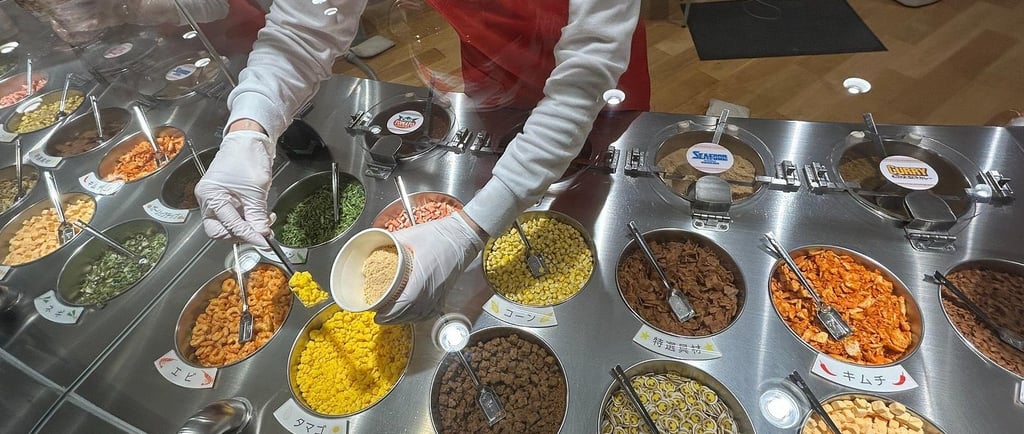 A staff member adds dried ingredients to a custom ramen cup at the Cup Noodles Museum's My Cupnoodles Factory.