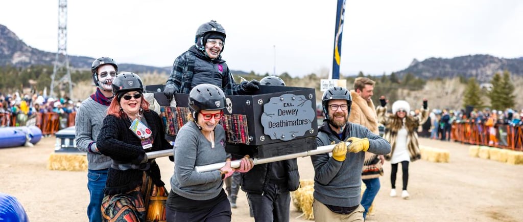 A costumed team carries a decorated coffin in a coffin race at a mountain winter festival.