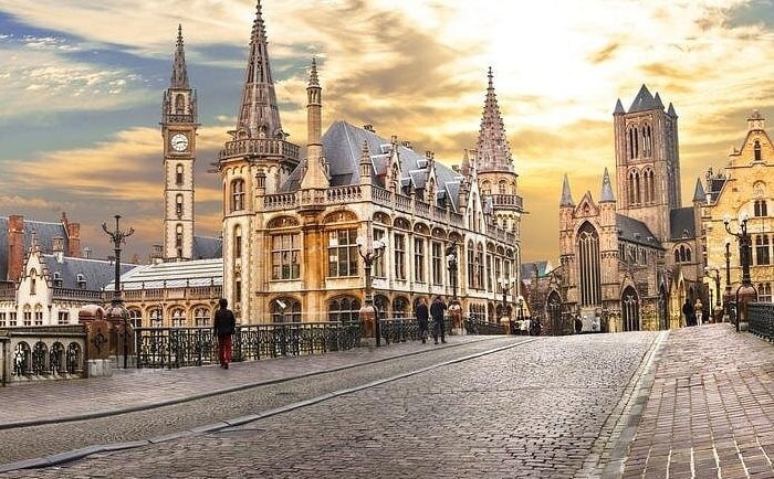 Historic medieval architecture of Ghent, Belgium, featuring Saint Bavo's Cathedral at sunset.
