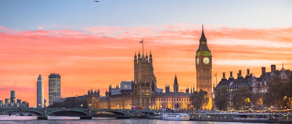 A panoramic view of Big Ben and the Houses of Parliament in London during a vibrant sunset over the River Thames.