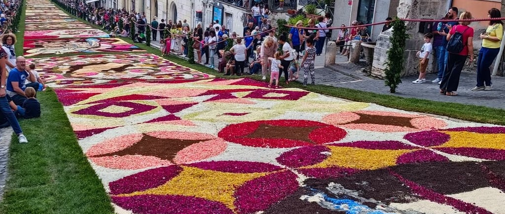 A colorful floral carpet mosaic lines a historic street during the Infiorata festival in Genzano, Italy.